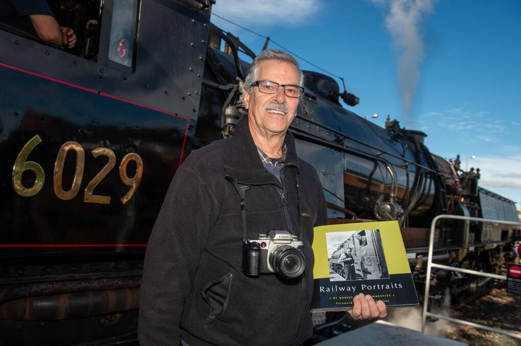 Bruce Wheatley alongside the Beyer-Garratt 6029 steam engine, with a copy of his book of Railway Photography. Picture by James Arrow